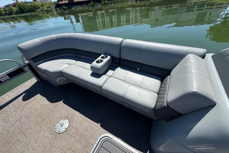 Slide: The Image of 2022 Ranger 223FC boat with gray seating and cup holders on a calm lake. - 12