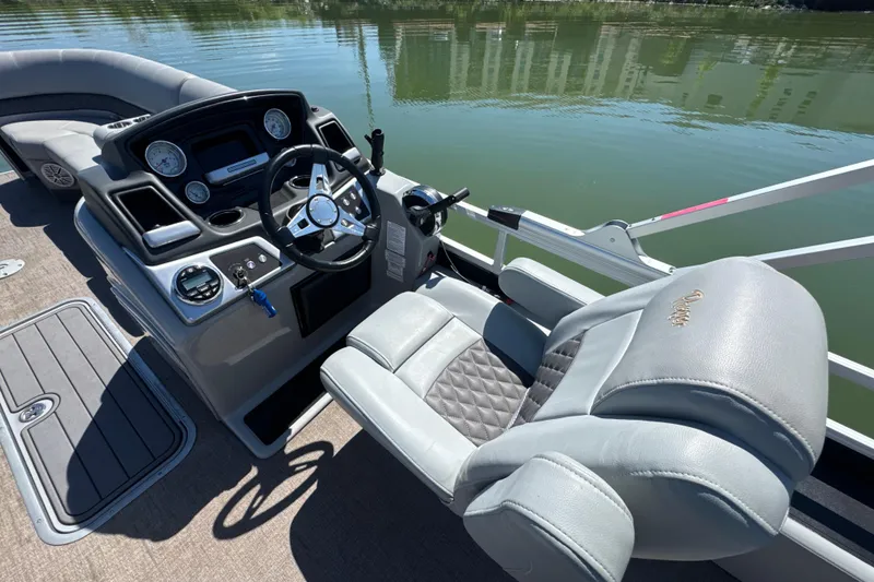Slide: The Image of 2022 Ranger 223FC boat cockpit with steering wheel and plush seating on calm water. - 15