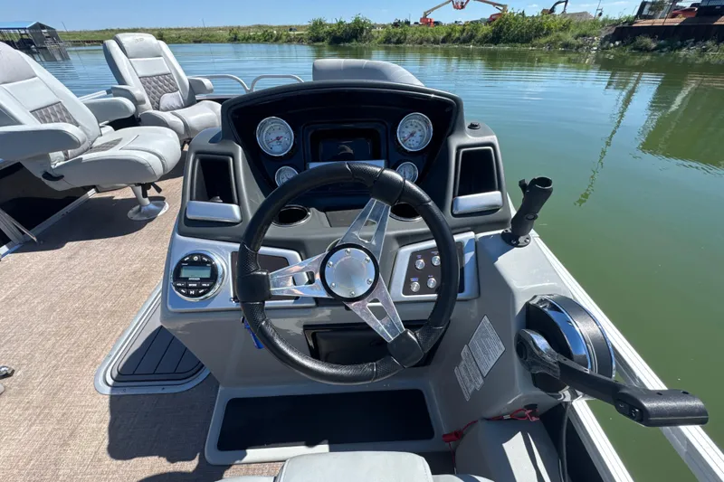 Slide: The Image of 2022 Ranger 223FC boat dashboard with steering wheel and controls on a calm lake. - 16