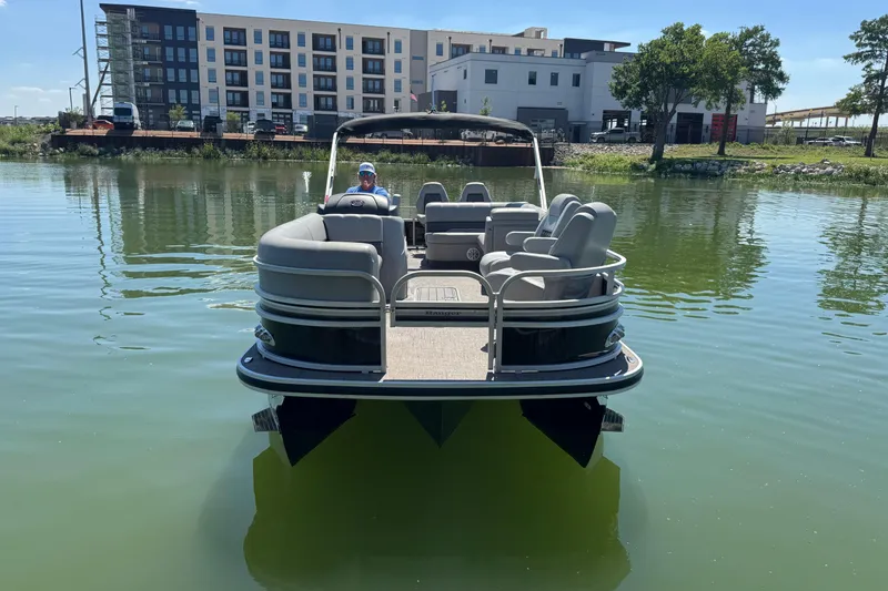 Slide: The Image of 2022 Ranger 223FC pontoon boat on calm water near modern buildings. - 2