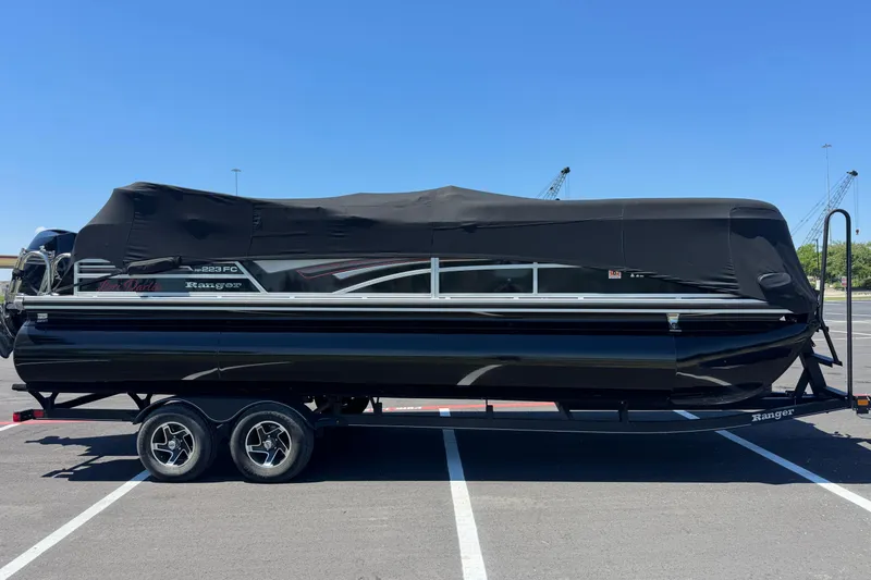 Slide: The Image of 2022 Ranger 223FC pontoon boat with black cover on trailer in parking lot. - 8