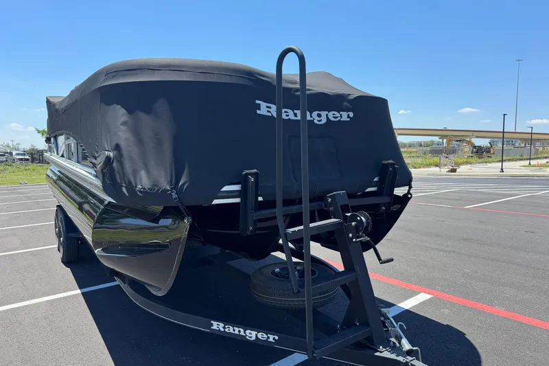 Slide: The Image of 2022 Ranger 223FC boat covered on trailer in parking lot under clear blue sky. - 9