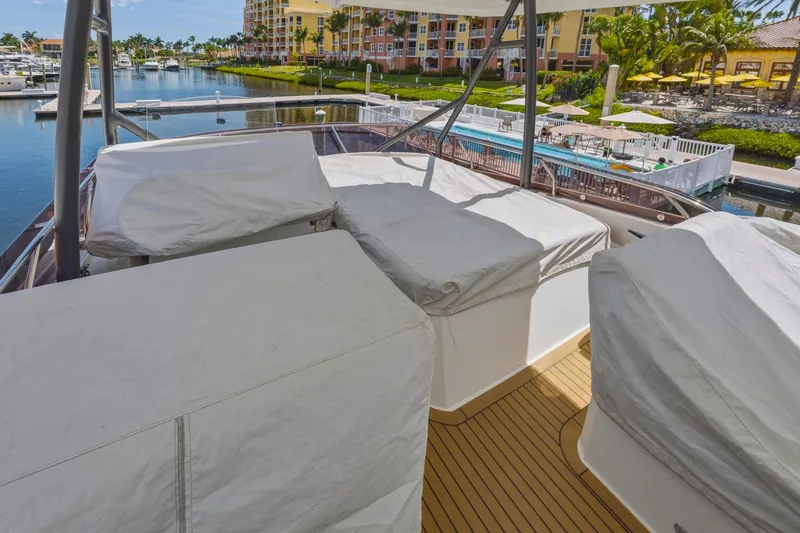 Slide: The Image of Luxury 2022 Prestige 520 yacht deck with covered seating, docked in a scenic marina. - 82