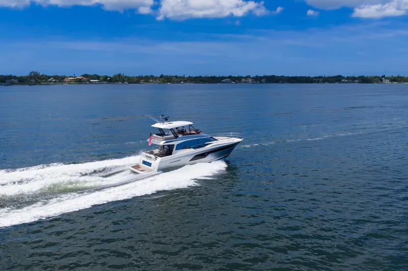 Slide: The Image of 2022 Prestige 520 yacht cruising on a serene blue lake under a clear sky. - 85