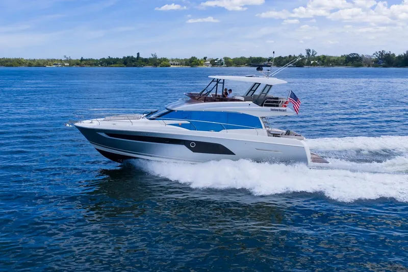 Slide: The Image of 2022 Prestige 520 yacht cruising on blue water under a clear sky. - 90