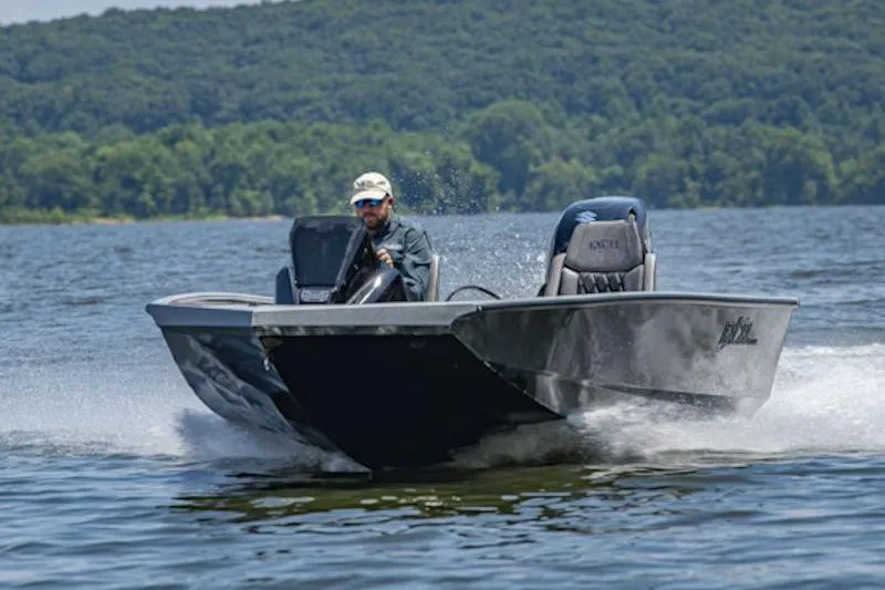 Slide: The Image of Man driving Excel EX 203 boat on a lake, 2026 model, with forested hills in background. - 2