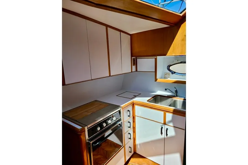Slide: The Image of 1989 TransWorld 39 Flushdeck Motor Yacht kitchen with stove, sink, and white cabinetry. - 12