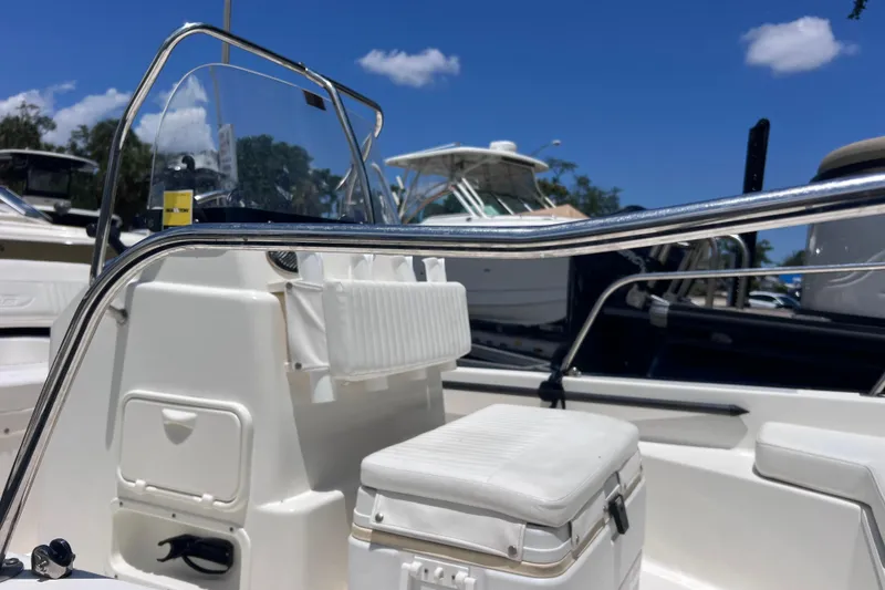 Slide: The Image of 2017 Boston Whaler 170 Montauk boat interior with seating and console, under clear blue sky. - 10