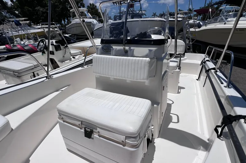 Slide: The Image of 2017 Boston Whaler 170 Montauk boat interior with seating and console, docked among other boats. - 21