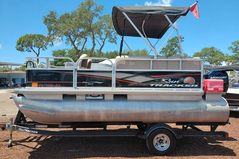 Slide: The Image of 2019 Sun Tracker Bass Buggy 16 DLX pontoon boat on trailer, with canopy and Mercury engine. - 4