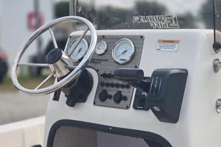 Slide: The Image of 2025 Carolina Skiff E18 JVX CC boat dashboard with steering wheel and control panel. - 18