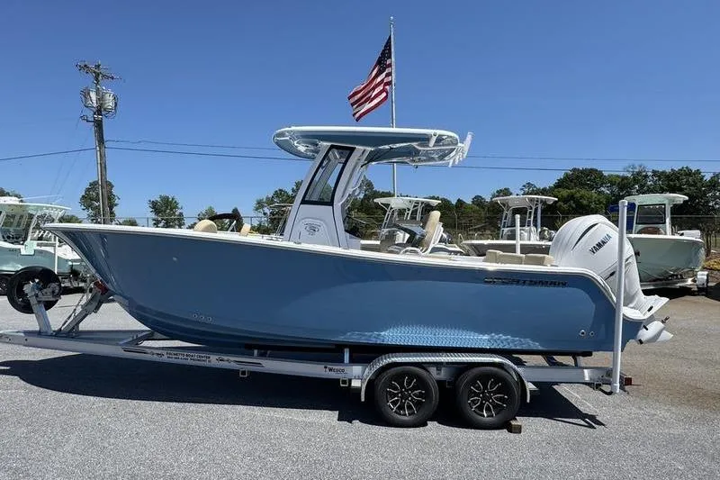The Image of 2026 Sportsman Heritage 231 Center Console boat on trailer, American flag in background. - 1