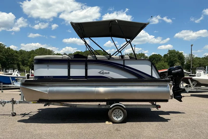 Slide: The Image of 2026 Qwest Lanai 816 pontoon boat with canopy, parked on trailer under blue sky. - 1