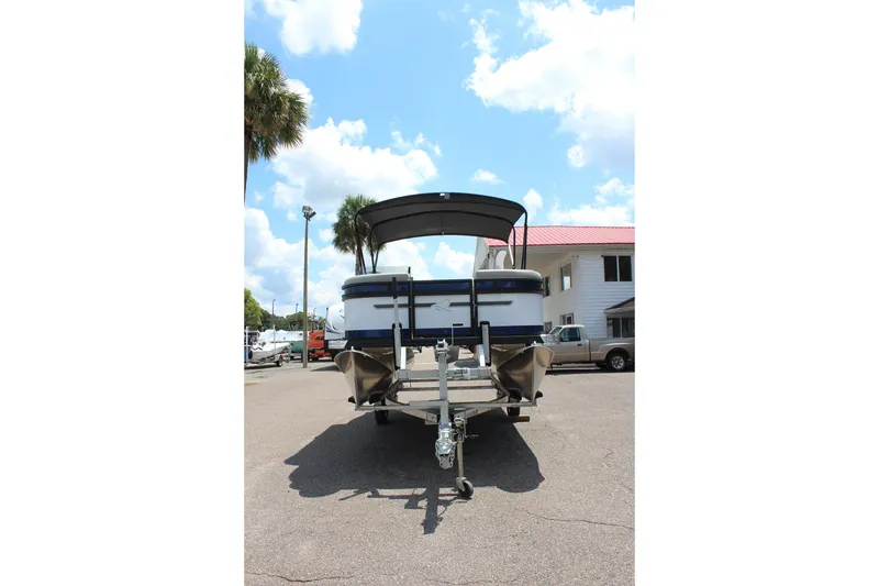 Slide: The Image of 2026 Qwest Lanai 816 pontoon boat on trailer, parked outdoors under a sunny sky. - 2