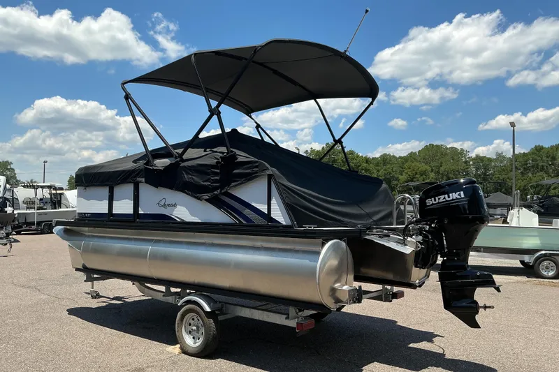 Slide: The Image of 2026 Qwest Lanai 816 pontoon boat with Suzuki motor on trailer, under blue sky. - 24