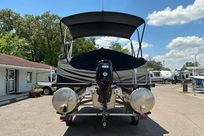 Slide: The Image of 2026 Qwest Lanai 816 pontoon boat with canopy and outboard motor in a dealership lot. - 25
