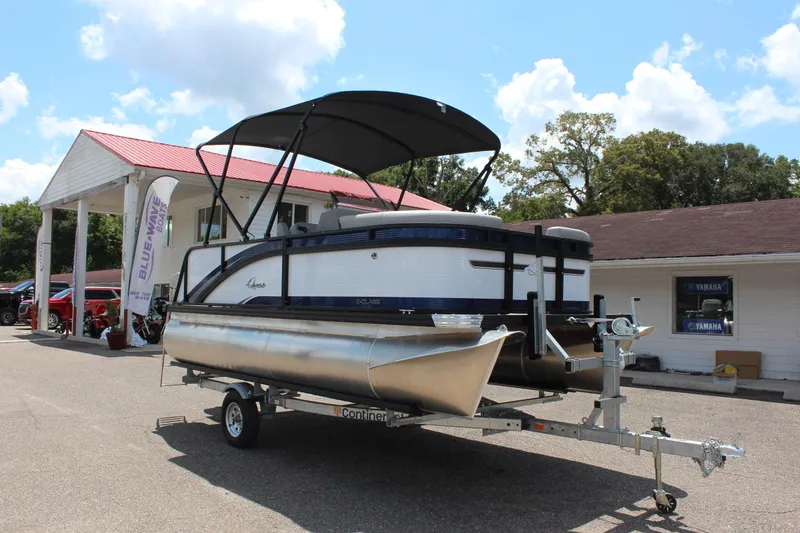 Slide: The Image of 2026 Qwest Lanai 816 pontoon boat on trailer at dealership under blue sky. - 3