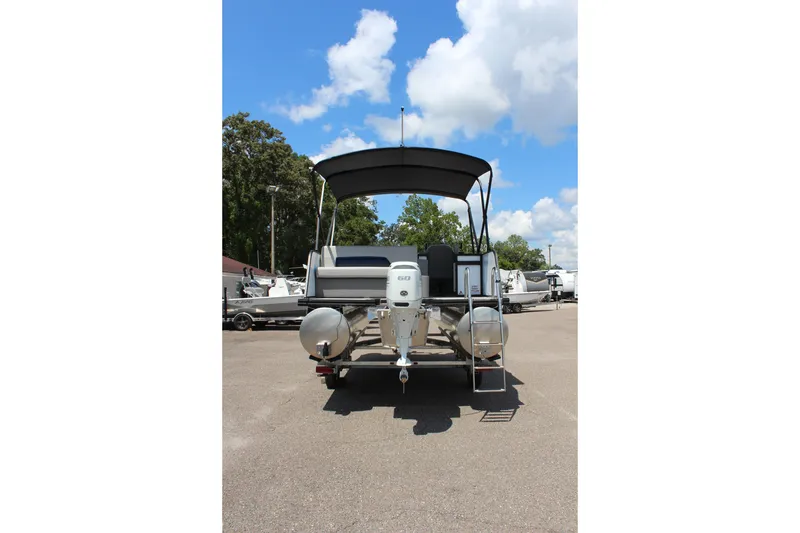 Slide: The Image of 2026 Qwest Lanai 816 pontoon boat, rear view, parked under a clear blue sky. - 4