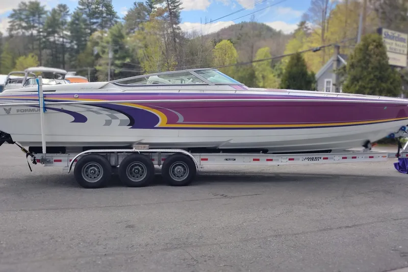 Slide: The Image of 2006 Formula 353 FASTech boat with vibrant purple and yellow design on a trailer. - 4