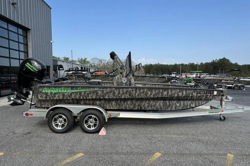 Slide: The Image of 2023 Havoc 1756 MRST boat on trailer, camo design, parked outdoors. - 13