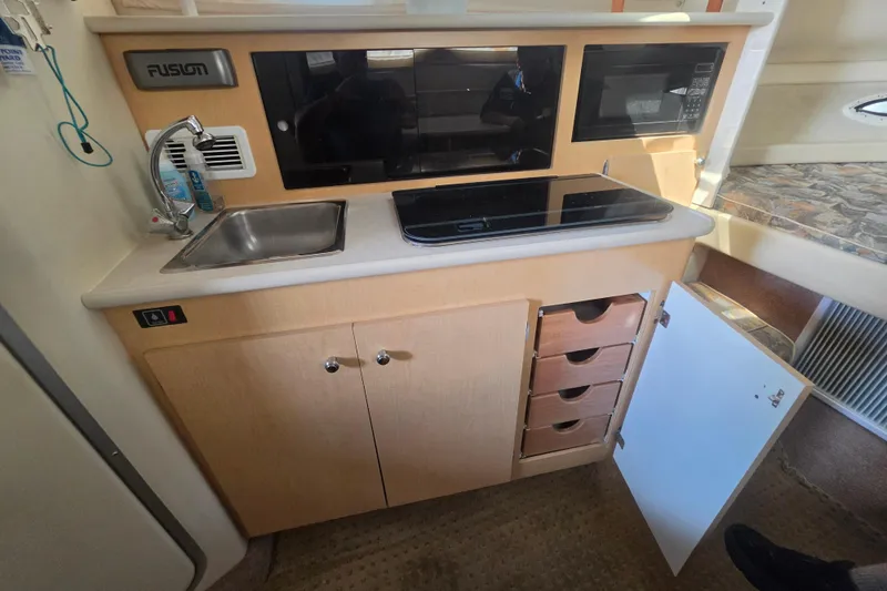 Slide: The Image of Interior of 2000 Bayliner 2855 Ciera showing kitchenette with sink, stove, and storage. - 21