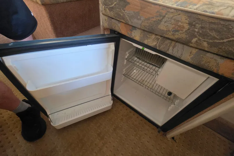 Slide: The Image of Open mini fridge inside 2000 Bayliner 2855 Ciera boat, showing empty shelves and door storage. - 22
