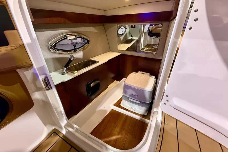 Slide: The Image of Interior of 2023 Chaparral 270 OSX boat featuring a compact sink and portable toilet. - 31