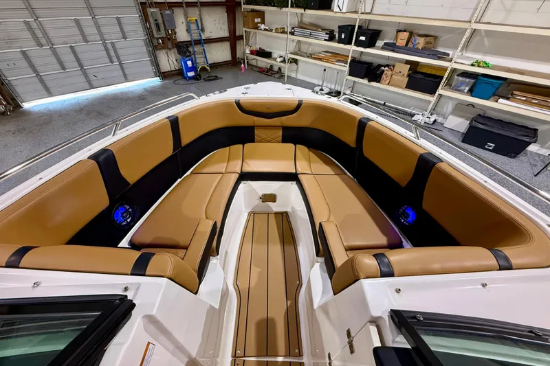 Slide: The Image of 2023 Chaparral 270 OSX boat interior with tan seating in a garage setting. - 32