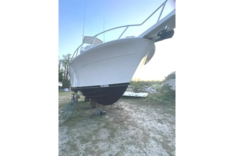 Slide: The Image of 1993 Blackfin 31 Combi boat on land, white hull, supported by stands. - 2