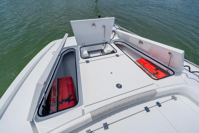 Slide: The Image of Open storage compartments on a 2023 Freeman 28 boat, containing life jackets. - 16