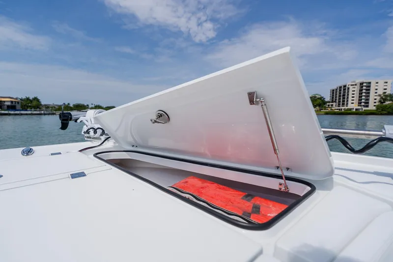 Slide: The Image of Open storage compartment on 2023 Freeman 28 boat, with life jacket inside, near waterfront. - 18