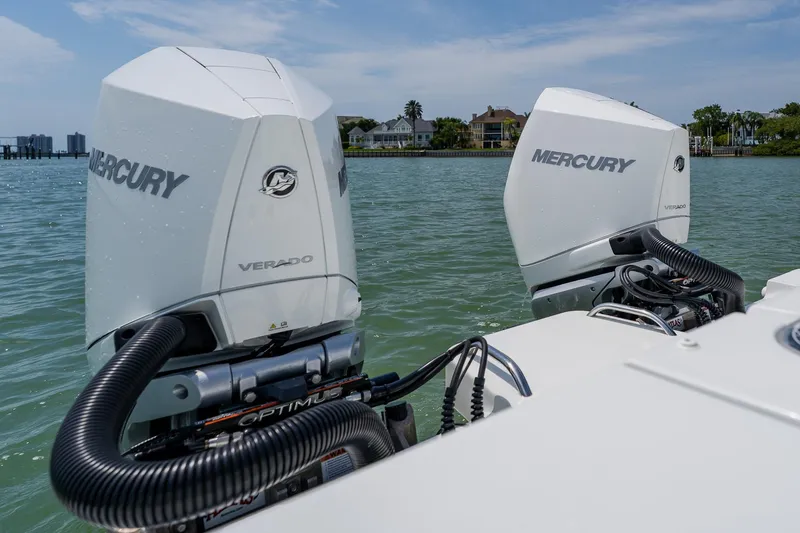 Slide: The Image of Twin Mercury Verado engines on a 2023 Freeman 28 boat, docked near waterfront homes. - 47