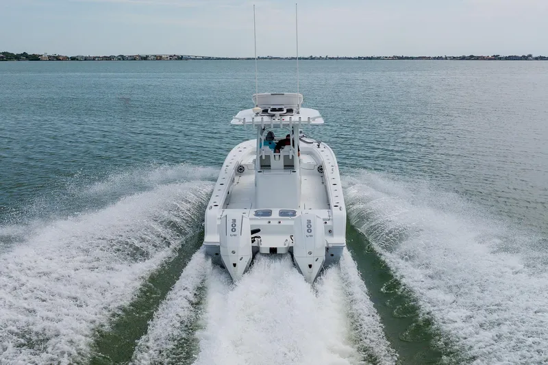 Slide: The Image of 2023 Freeman 28 boat cruising on open water, rear view with twin engines. - 8