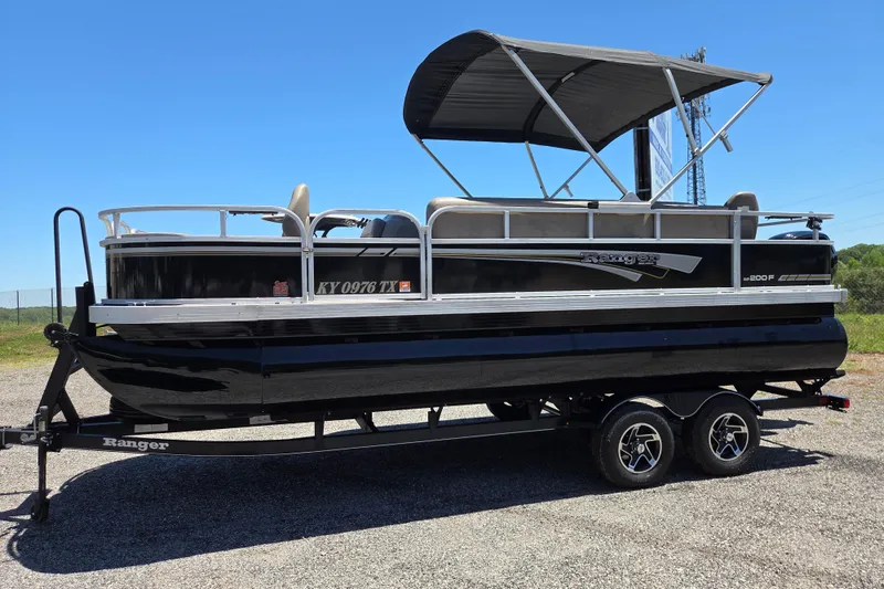 The Image of 2023 Ranger Reata 200F pontoon boat on trailer under clear blue sky. - 0