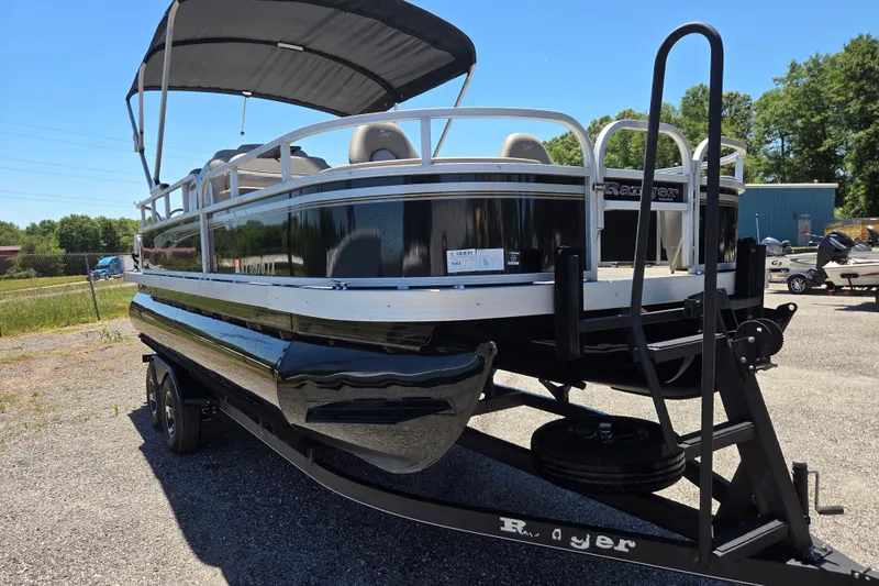 Slide: The Image of 2023 Ranger Reata 200F pontoon boat on trailer, parked outdoors under clear sky. - 2