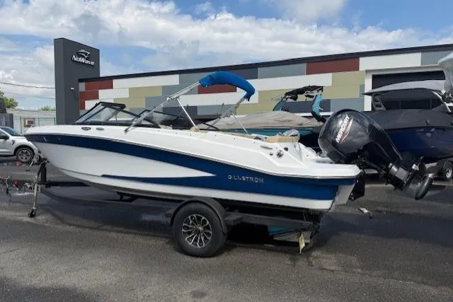 Slide: The Image of 2022 Glastron GX 210 Sport boat on trailer, parked outdoors near dealership. - 1
