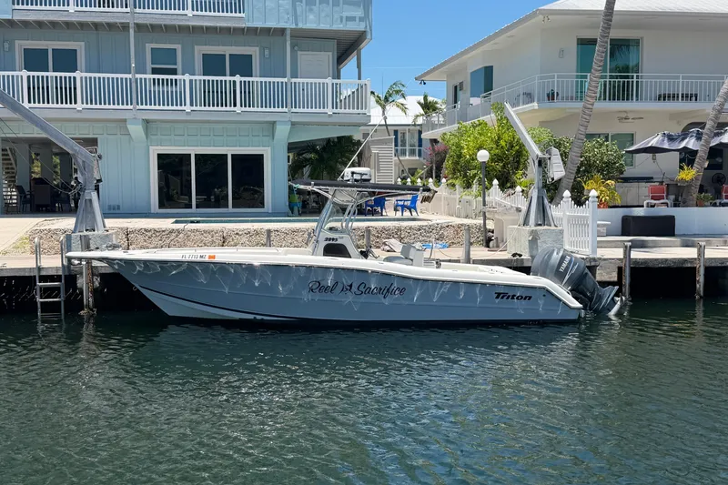 The Image of 2004 Triton 2895 CC boat docked by waterfront homes, featuring dual engines. - 1
