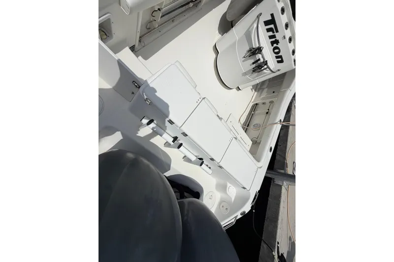 Slide: The Image of 2004 Triton 2895 CC boat interior with fishing rod holders and storage compartments. - 10