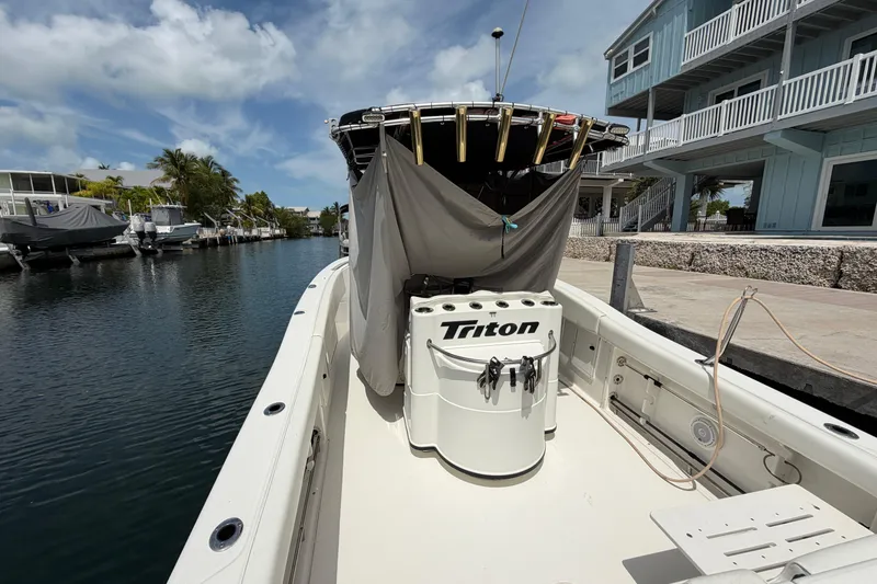 Slide: The Image of 2004 Triton 2895 CC boat docked by waterfront homes under a clear blue sky. - 11