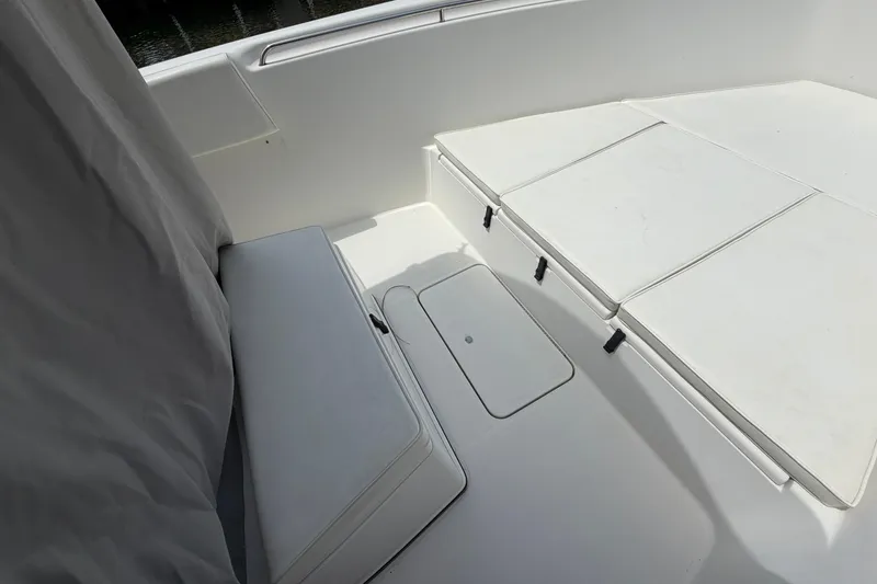 Slide: The Image of 2004 Triton 2895 CC boat interior with white cushioned seating and storage compartments. - 14