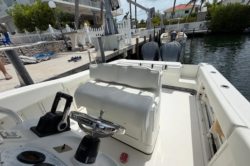 Slide: The Image of 2004 Triton 2895 CC boat interior at dock, featuring steering console and seating. - 16
