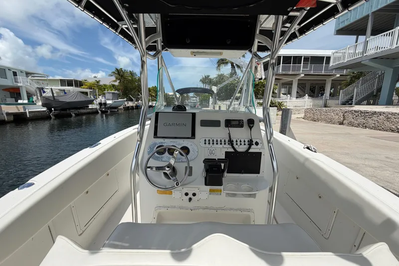Slide: The Image of 2004 Triton 2895 CC boat cockpit with Garmin navigation, docked by waterfront homes. - 17