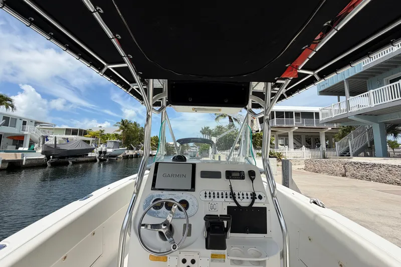Slide: The Image of 2004 Triton 2895 CC boat cockpit with Garmin navigation, docked near waterfront homes. - 18