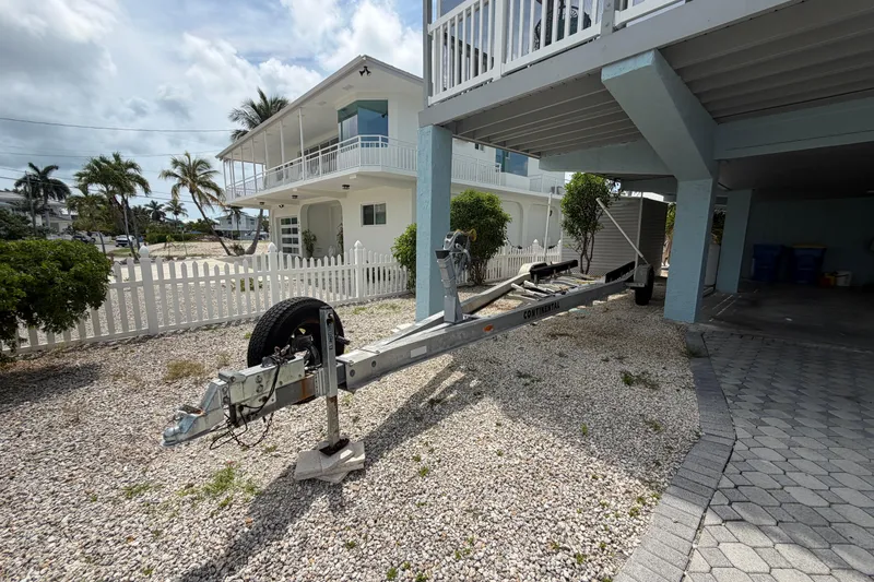 Slide: The Image of Boat trailer parked under elevated house, Triton 2895 CC, 2004 model, with palm trees in background. - 33