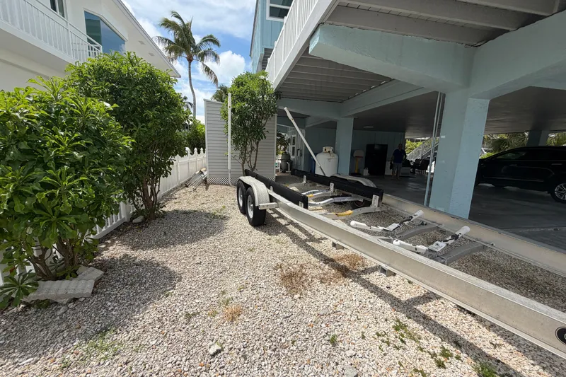 Slide: The Image of Boat trailer parked under a building, surrounded by greenery, Triton 2895 CC, 2004 model. - 34