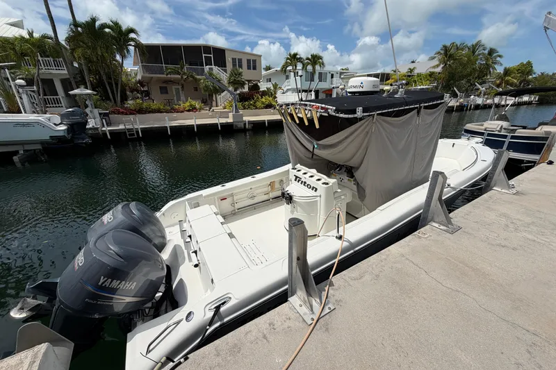 Slide: The Image of 2004 Triton 2895 CC boat docked with Yamaha engines, surrounded by waterfront homes. - 6
