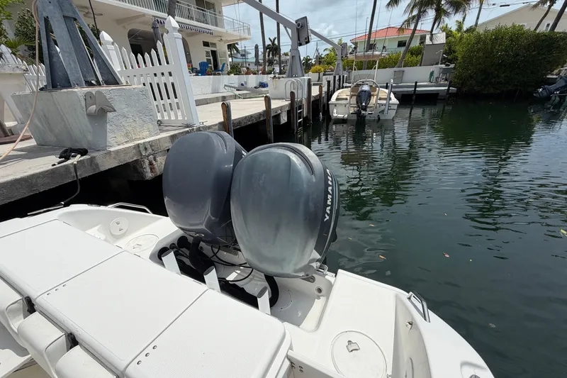 Slide: The Image of 2004 Triton 2895 CC boat with dual Yamaha engines docked by waterfront homes. - 7