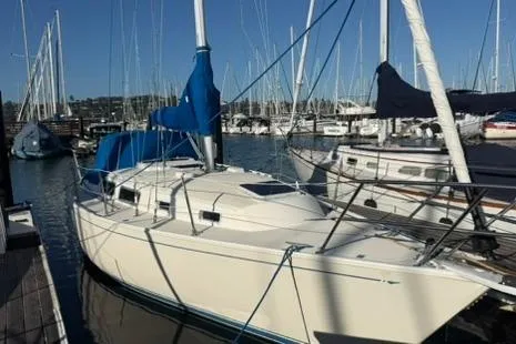 The Image of 1985 Sabre 32 sailboat docked in marina, surrounded by other boats under clear blue sky. - 1
