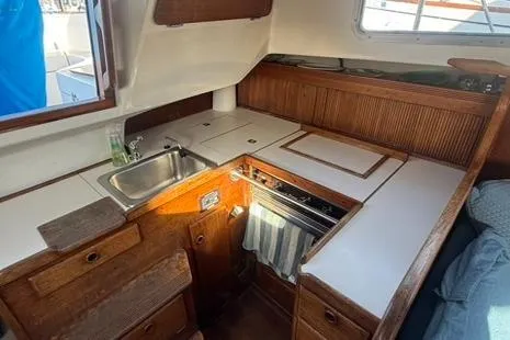 Slide: The Image of 1985 Sabre 32 sailboat interior kitchen with wooden cabinetry and compact design. - 11