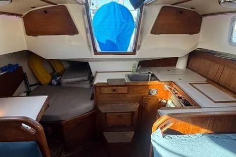 Slide: The Image of 1985 Sabre 32 sailboat interior with wood cabinetry, compact kitchen, and seating area. - 12